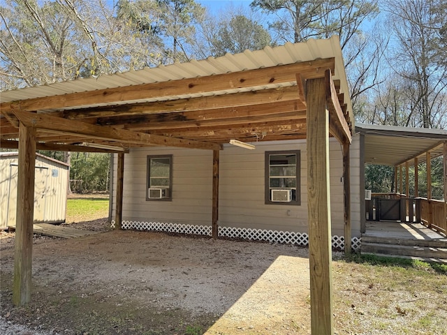 exterior space with a storage unit, cooling unit, an attached carport, and an outdoor structure