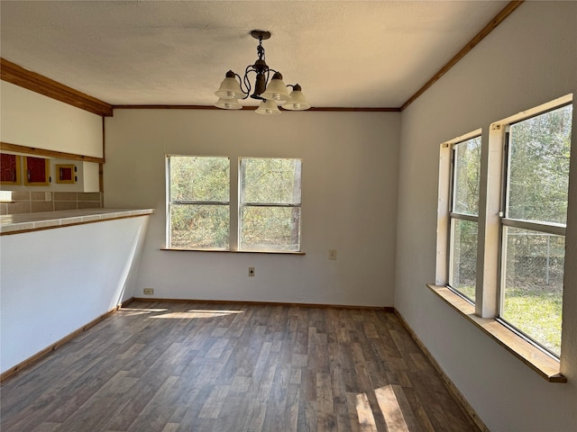 unfurnished dining area featuring crown molding, baseboards, dark wood-type flooring, and a chandelier