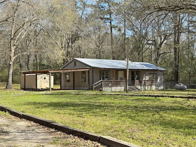 view of front facade with a front yard, an outbuilding, covered porch, a carport, and a storage shed