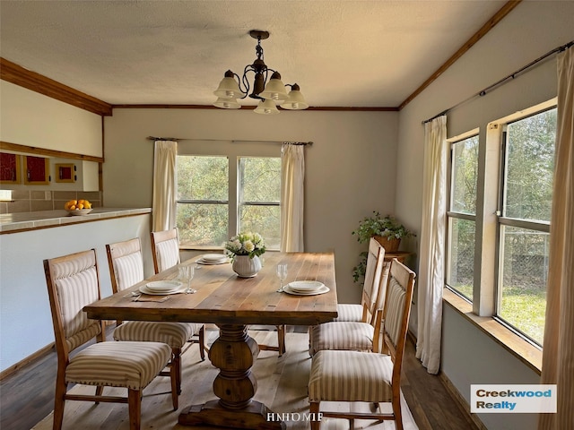 dining room with wood finished floors, baseboards, a textured ceiling, crown molding, and a chandelier