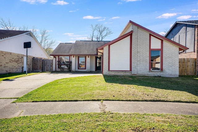 mid-century inspired home featuring a front yard, fence, and brick siding