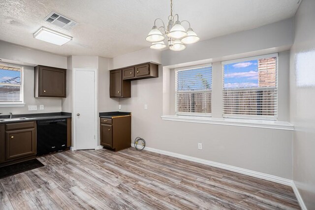 kitchen featuring visible vents, light wood finished floors, black dishwasher, dark brown cabinets, and dark countertops