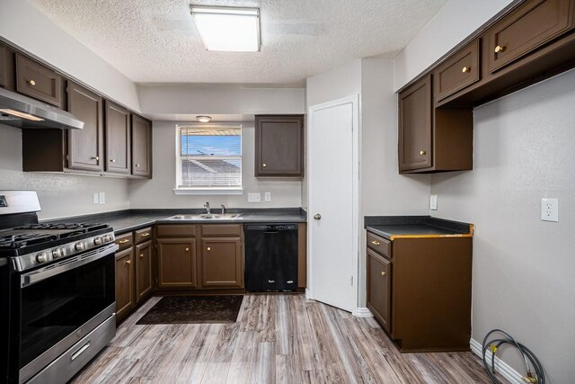 kitchen with dark countertops, a sink, black dishwasher, gas range, and wall chimney exhaust hood