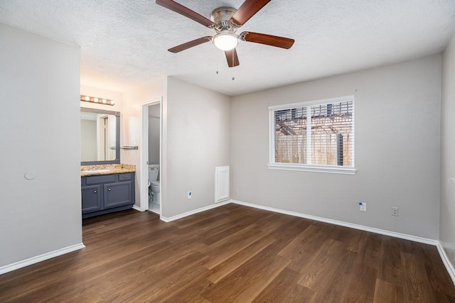 unfurnished bedroom featuring a textured ceiling, baseboards, and dark wood-style flooring