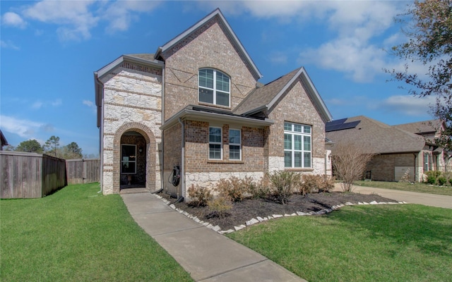 view of front of home featuring a front lawn, fence, brick siding, and stone siding