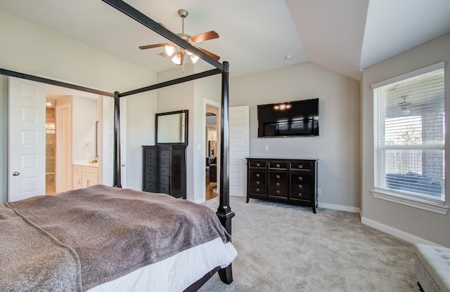 bedroom featuring baseboards, light colored carpet, vaulted ceiling, ensuite bathroom, and a ceiling fan