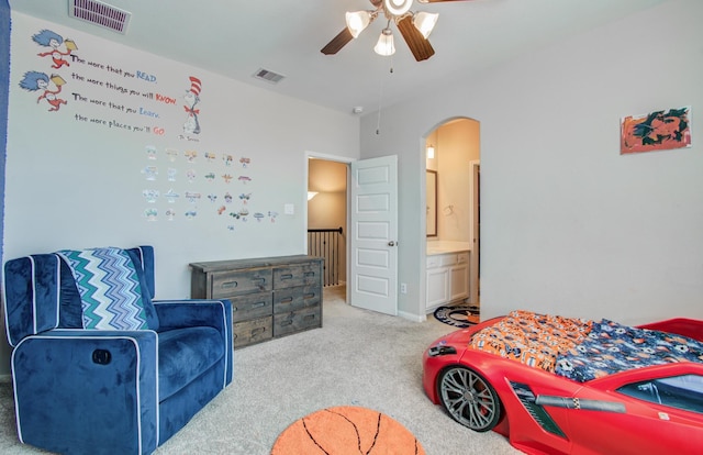 carpeted bedroom with a ceiling fan, ensuite bath, arched walkways, and visible vents