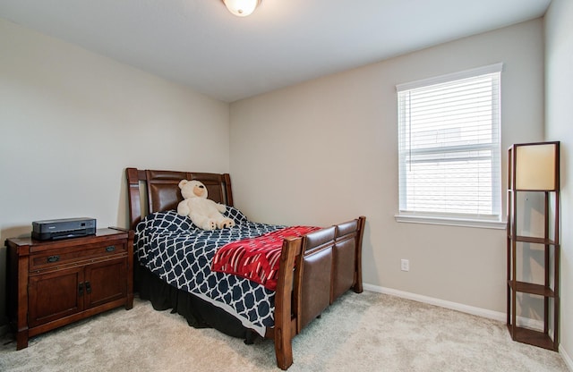 bedroom with light colored carpet and baseboards