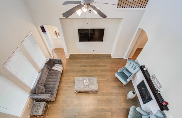 living room with arched walkways, baseboards, a ceiling fan, and wood finished floors