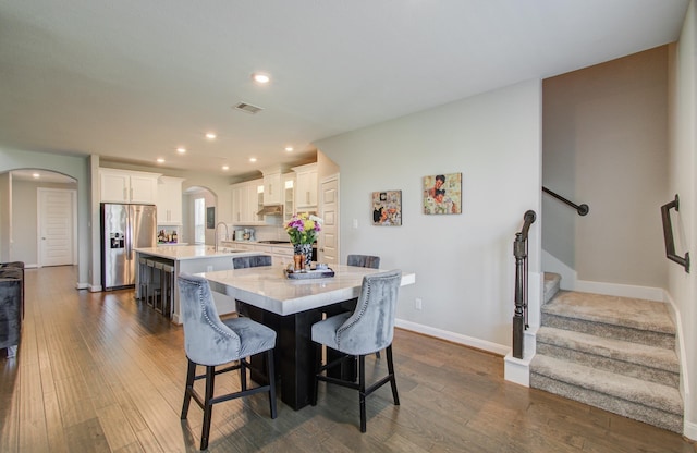 dining area featuring visible vents, baseboards, arched walkways, dark wood-style flooring, and stairs