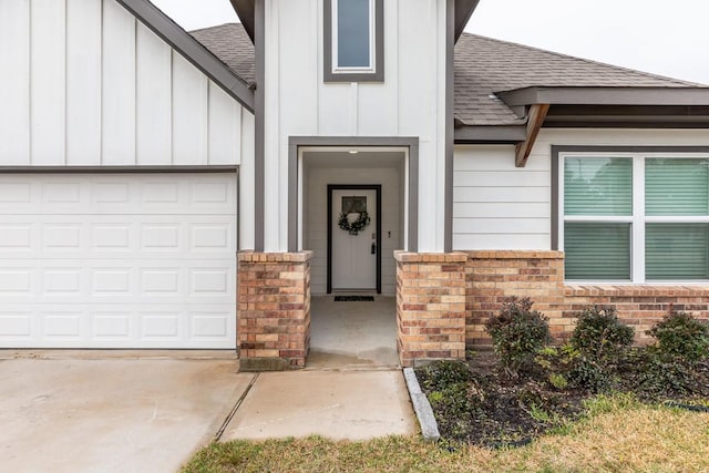 property entrance with a garage, brick siding, board and batten siding, and roof with shingles