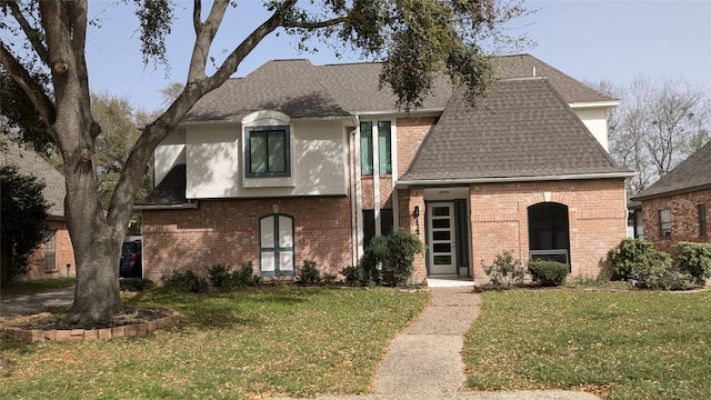 view of front of house featuring brick siding, stucco siding, a shingled roof, and a front yard