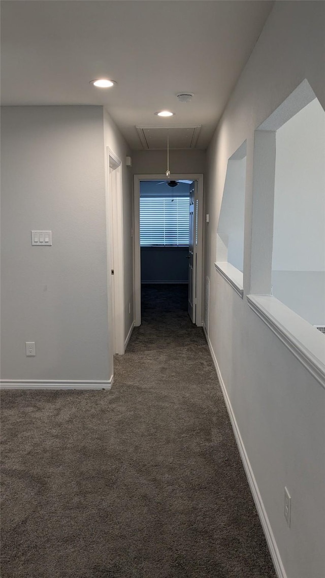 hall with baseboards, attic access, and carpet