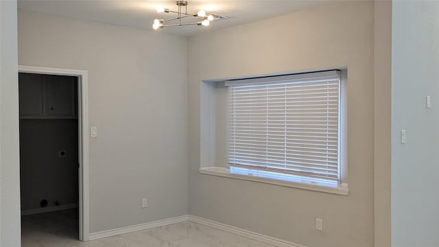 unfurnished room featuring a notable chandelier, baseboards, and marble finish floor