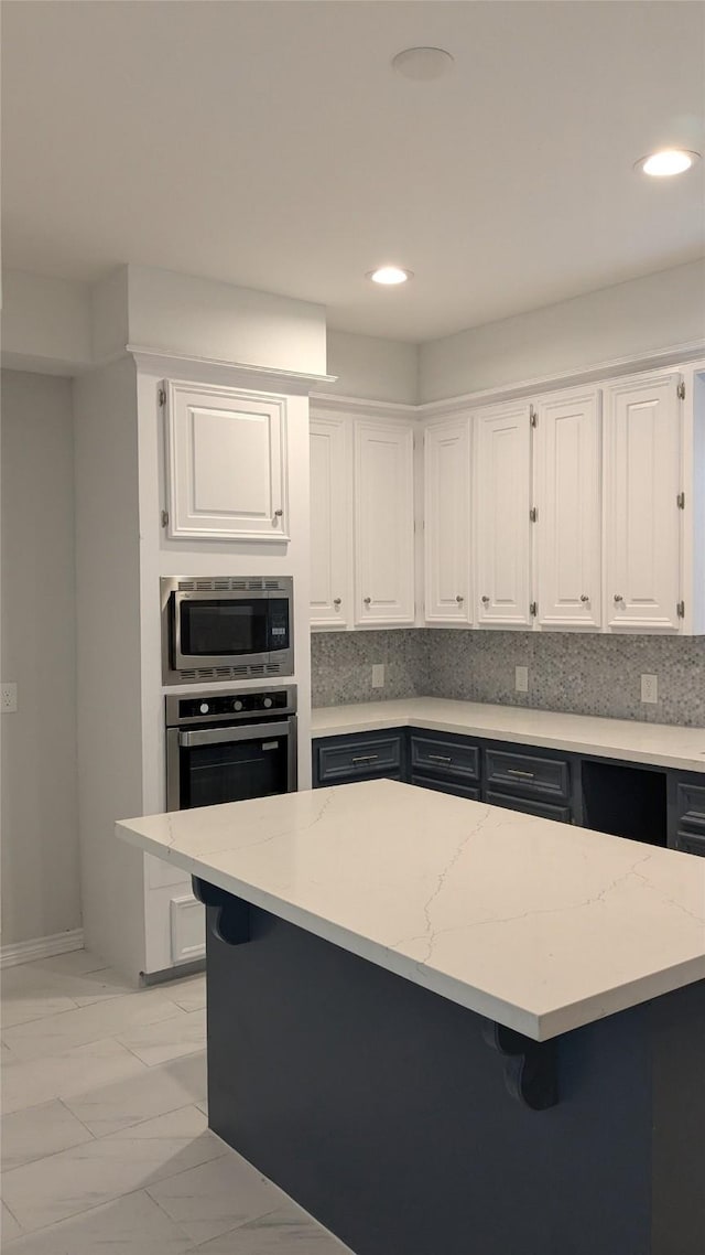 kitchen with stainless steel appliances, marble finish floor, white cabinets, and decorative backsplash