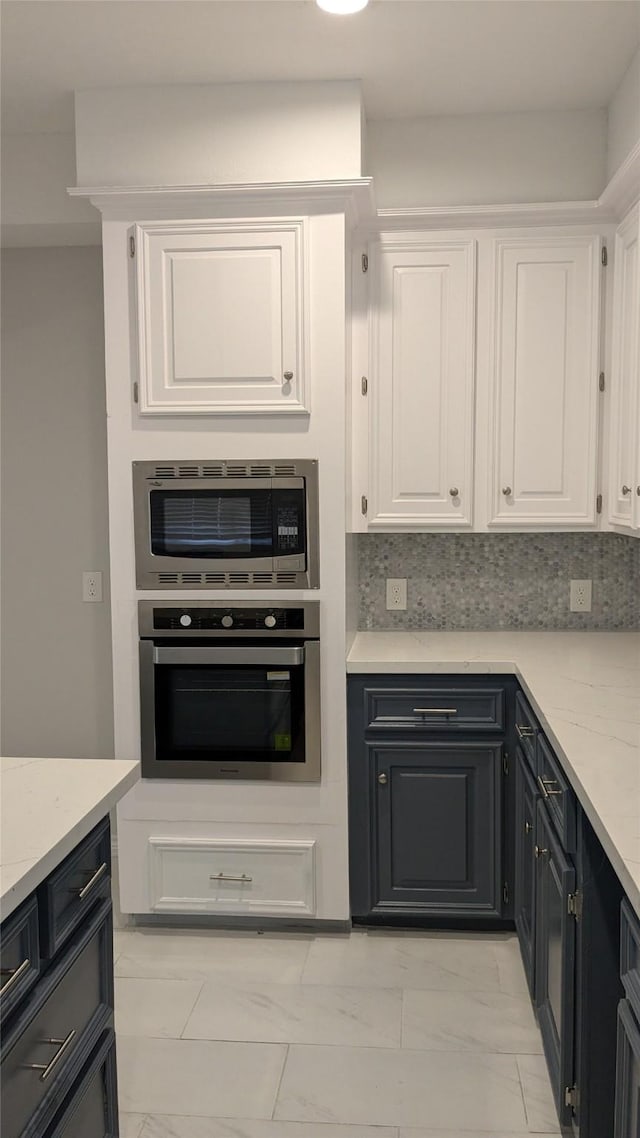 kitchen with stainless steel appliances, marble finish floor, decorative backsplash, and white cabinetry