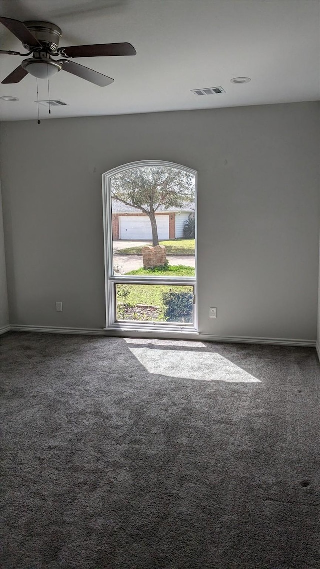 carpeted empty room with baseboards, visible vents, and ceiling fan