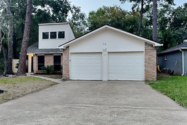 view of front of house with brick siding, a shingled roof, concrete driveway, stucco siding, and an attached garage