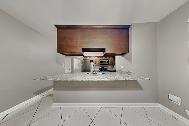 kitchen with a peninsula, light tile patterned floors, appliances with stainless steel finishes, and a sink