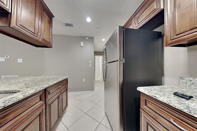 kitchen featuring visible vents, freestanding refrigerator, recessed lighting, light tile patterned floors, and light stone countertops