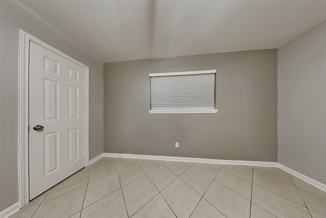 spare room with light tile patterned floors and baseboards