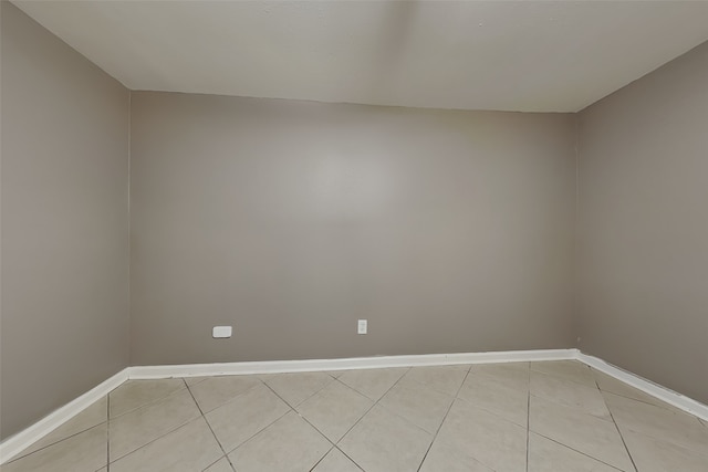 empty room with light tile patterned floors and baseboards