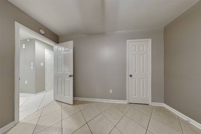 empty room featuring light tile patterned floors and baseboards