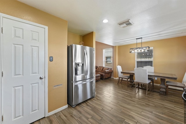 kitchen featuring visible vents, baseboards, wood finished floors, and stainless steel fridge with ice dispenser