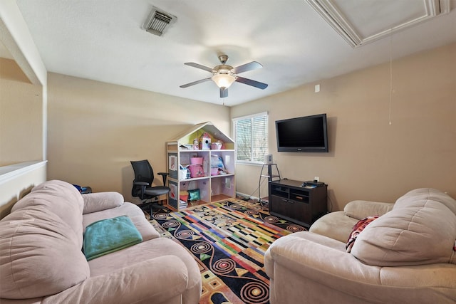 living room with visible vents, attic access, and a ceiling fan