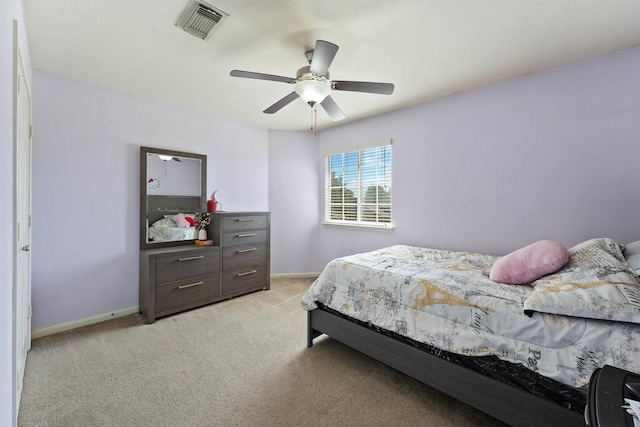 bedroom with visible vents, light colored carpet, baseboards, and ceiling fan