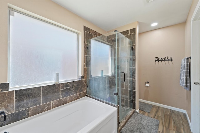 full bathroom with wood finished floors, baseboards, a bath, and a shower stall