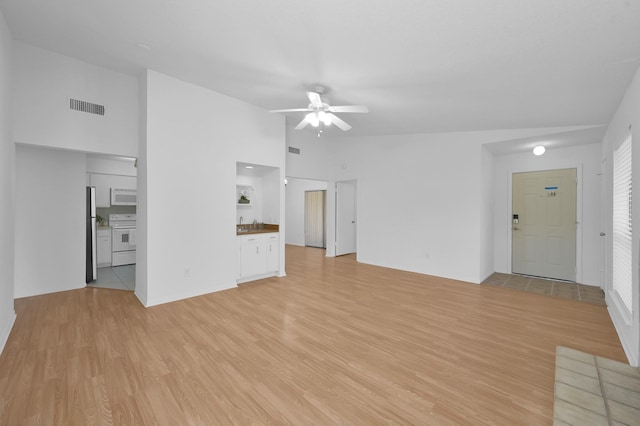 unfurnished living room with visible vents, lofted ceiling, light wood-type flooring, and a ceiling fan