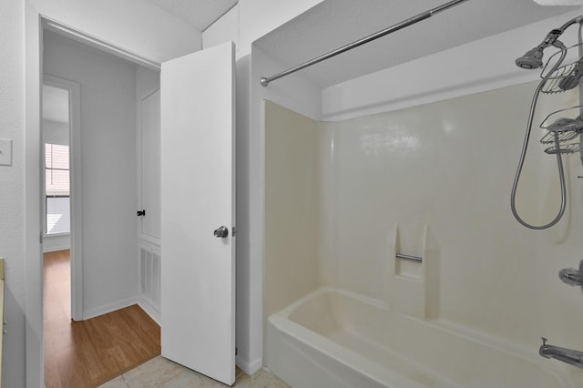 bathroom with shower / bath combination, baseboards, visible vents, and wood finished floors