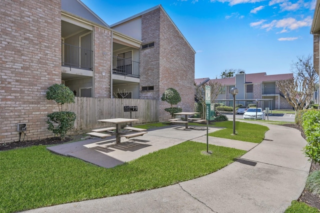 view of property's community with a lawn and fence