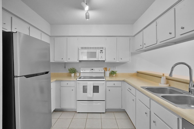 kitchen featuring white appliances, light tile patterned floors, a sink, light countertops, and white cabinetry