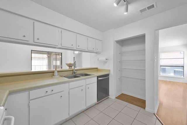 kitchen with visible vents, a sink, stainless steel dishwasher, white cabinetry, and light countertops