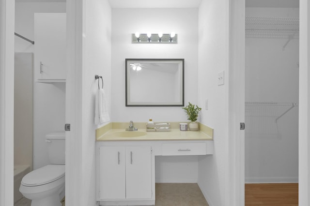 bathroom with a spacious closet, a shower, toilet, and vanity