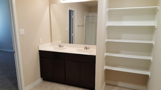 bathroom featuring tile patterned floors, double vanity, baseboards, and a sink