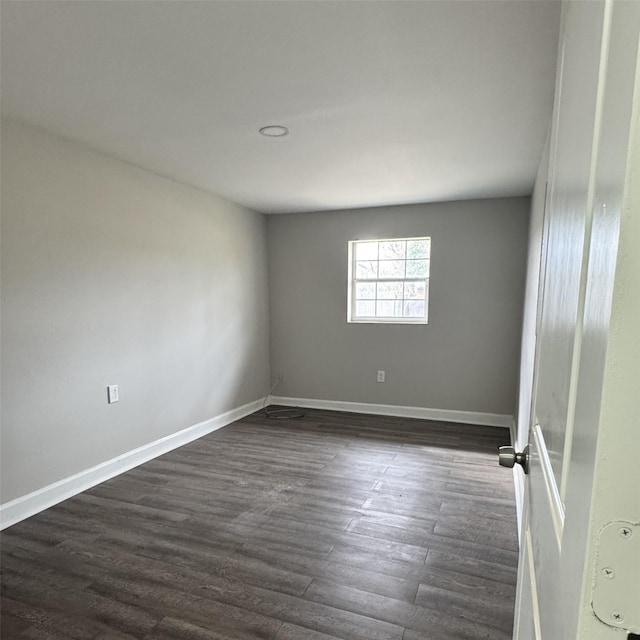 unfurnished room featuring dark wood-type flooring and baseboards