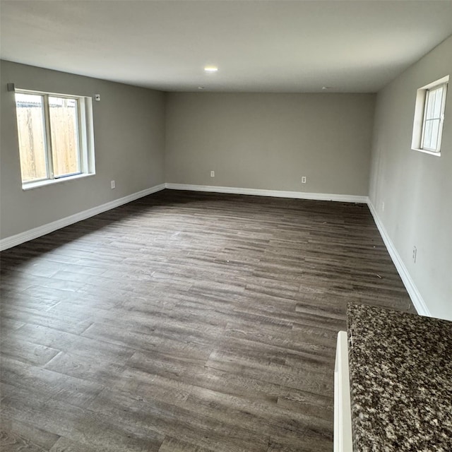 spare room featuring baseboards, plenty of natural light, and dark wood-type flooring