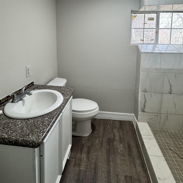 bathroom with toilet, vanity, baseboards, and wood finished floors