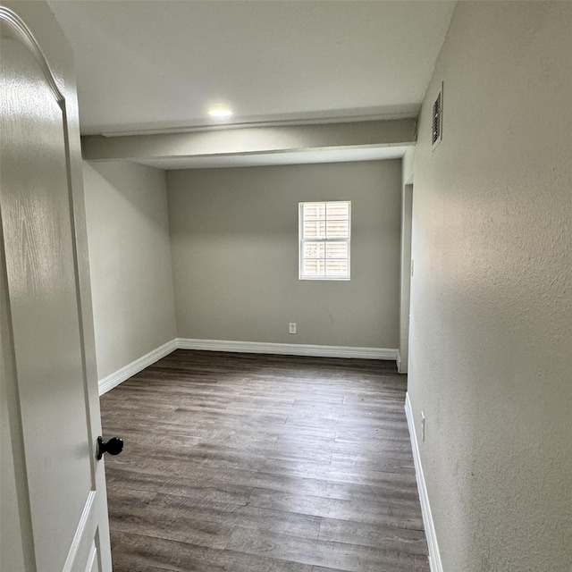 unfurnished room featuring dark wood-style floors, visible vents, and baseboards