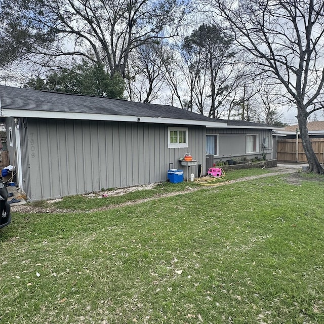 back of house with cooling unit, a lawn, board and batten siding, and fence