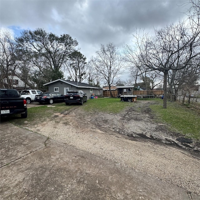 view of front facade with driveway, a front yard, and fence