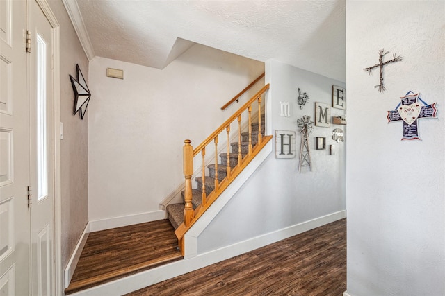 stairway featuring wood finished floors, baseboards, and a textured ceiling