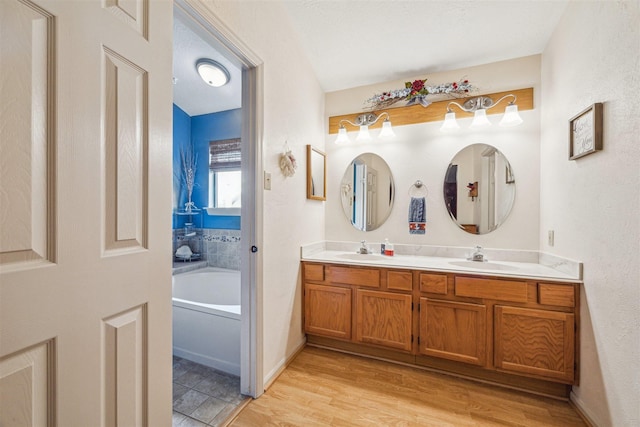 bathroom featuring double vanity, a garden tub, wood finished floors, and a sink