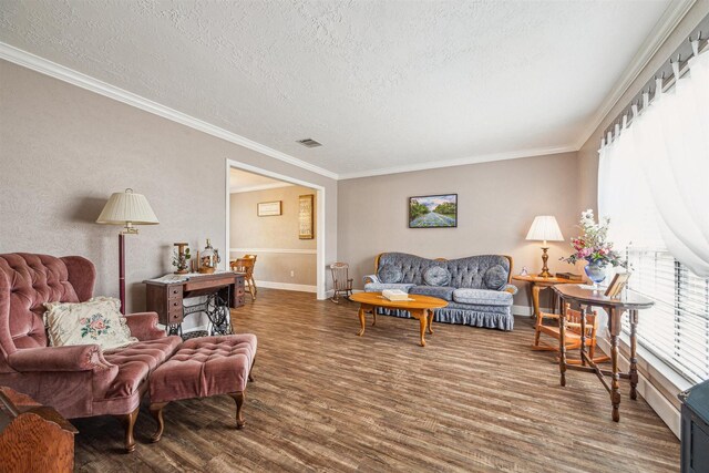 living area with visible vents, a textured ceiling, wood finished floors, and ornamental molding