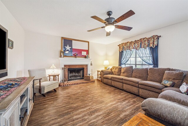 living area with ceiling fan, a brick fireplace, and wood finished floors