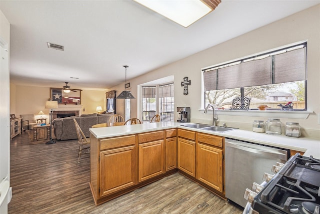 kitchen featuring wood finished floors, visible vents, a fireplace, a sink, and dishwasher