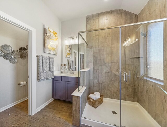 full bathroom with lofted ceiling, vanity, a shower stall, and baseboards